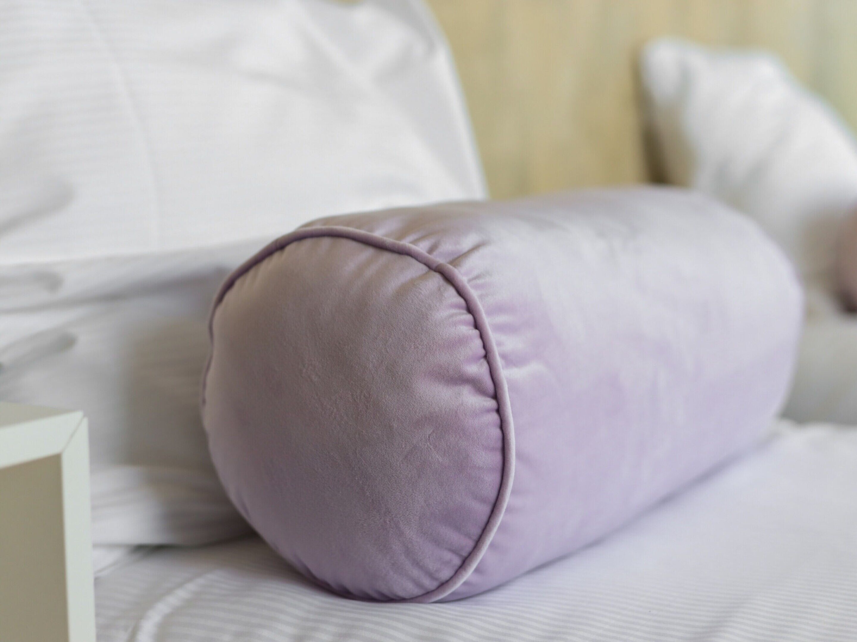 A bed with a white mattress and a purple pillow.