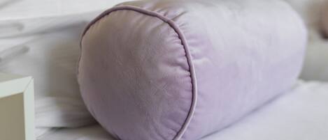 A bed with a white mattress and a purple pillow.