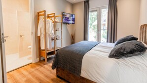Une chambre à coucher avec un lit, une télévision, une armoire en bois et une fenêtre avec des rideaux.