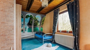 A room with a bed, a radiator, a window with curtains, a mural, and a brick wall. - Apartment in Holstein With Balcony (Ploen)