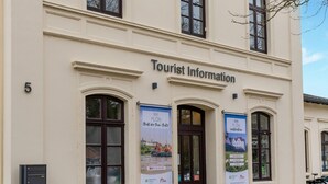 A building with the sign "Tourist Information" and multiple banners advertising activities. - Apartment in Holstein With Balcony (Ploen)