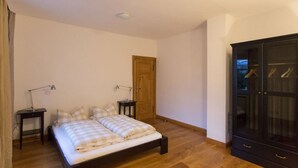 A bedroom with a wooden bed, two bedside tables with lamps, a wardrobe, and a door. - in the Estate Worker's House (Karstädt)
