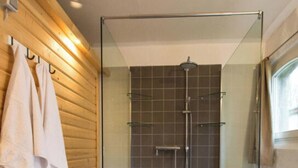 A modern bathroom with a glass shower enclosure, wooden wall paneling, and a small wooden bench. - in the Estate Worker's House (Karstädt)