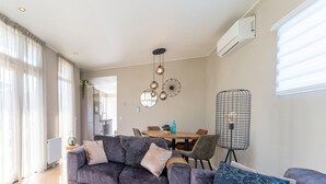 Ein modernes Wohnzimmer mit grauem Sofa, einem Holztisch und einem Essbereich mit Holztisch und Stühlen.