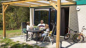 A covered patio with a table and chairs, a bike parked outside, and a house number 158 visible.