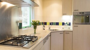 Una cocina moderna con estufa a gas, campana extractora de acero inoxidable, horno integrado y lavavajillas.