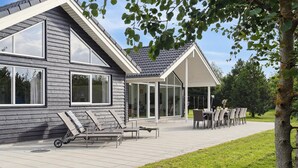 Een modern huis met grote ramen, een overdekt terras en buitenmeubilair.