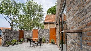 Eine Terrasse mit einer Steinmauer, einem Holztisch und Stühlen.