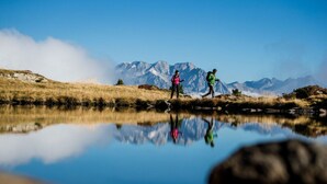 A tranquil lake with mountains in the background and two people standing on the shore. - Apartment in St. Jakob im Ahrntal Sudtirol (Valle Aurina)