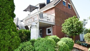 A two-story brick house with a balcony, surrounded by greenery. - Holiday Apartment Elbe (Drochtersen)