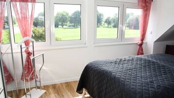 A bedroom with a bed, two windows, and a radiator.