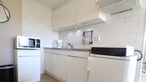 A compact kitchen with white cabinets, a microwave, a coffee maker, and a small refrigerator. - Holiday Home in Donkerbroek Near Forest Trails (Donkerbroek)