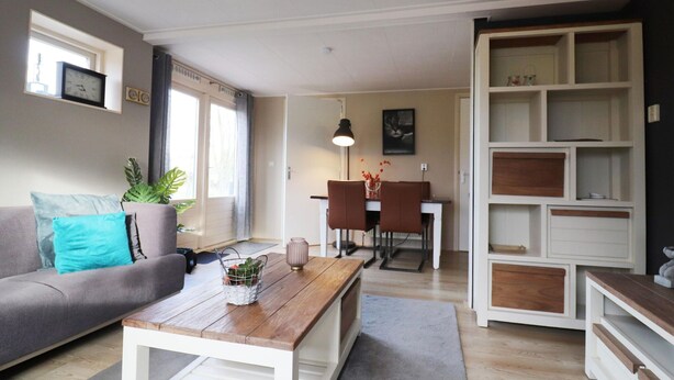 A living room with a sofa, coffee table, and dining area. - Holiday Home in Donkerbroek Near Forest Trails (Donkerbroek)