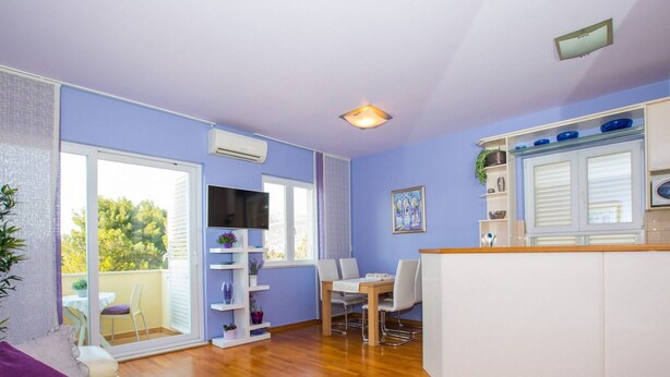 A compact living space with a dining area, kitchenette, and a balcony with a view of trees. - Apartment 3 Beaches With Free Parking (Dubrovnik)