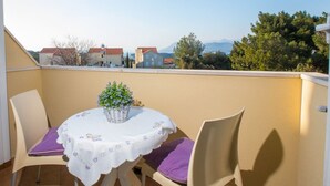 A balcony with a table and chairs, a small potted plant, and a view of buildings and trees. - Apartment 3 Beaches With Free Parking (Dubrovnik)
