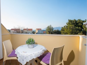 Enjoy a romantic meal for two on this balcony with a table set amidst a serene residential view.