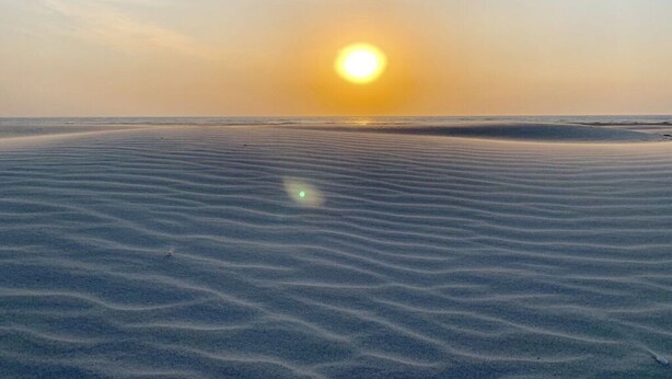 A beach with a clear sky and the sun setting or rising over the water. - Watt`n Flair on the North Beach (Borkum)