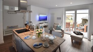 A modern kitchen with a dining area, a TV, and a view of the outdoors. - Watt`n Flair on the North Beach (Borkum)