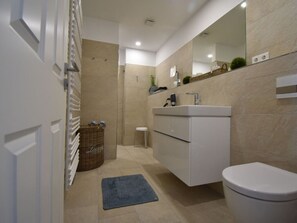 A modern bathroom with a white vanity, a large mirror, and a toilet. - Watt`n Flair on the North Beach (Borkum)