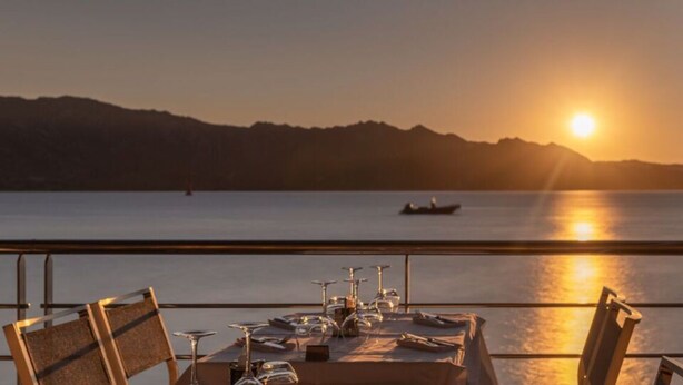 A table set for dining with a view of the sea and mountains at sunset. - Fordebrise Modern Retreat (Steinberg)