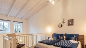 A bedroom with a bed, a crib, and a window with a view of trees. - Fordebrise Modern Retreat (Steinberg)