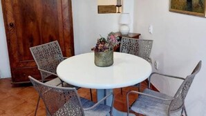 A dining area with a round table, four chairs, a vase with flowers, a lamp, and a painting on the wall. - Apartment Regina - Duplex Two Bedroom Apartment (Split)