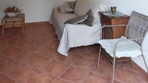 A cozy room with a bed, a small table with a plant, a chair, and a painting on the wall. - Apartment Regina - Duplex Two Bedroom Apartment (Split)