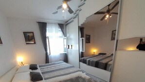 A hotel room with a bed, bedside tables, a mirror, and a ceiling fan. - Apartment Regina - Duplex Two Bedroom Apartment (Split)