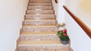 A staircase with a wooden handrail and a potted plant at the bottom. - Apartment Regina - Duplex Two Bedroom Apartment (Split)