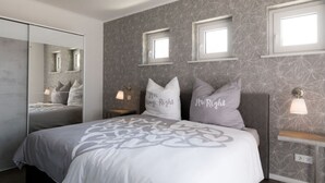 A modern bedroom with a large bed, two bedside tables with lamps, a wardrobe, and a mirror. - Casa sul Lago Modern Retreat (Werder (Havel))