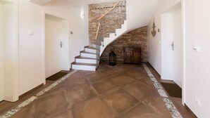A spacious hallway with a curved ceiling, a brick wall, and a staircase with a metal railing. - Casa sul Lago Modern Retreat (Werder (Havel))