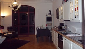 Een kleine keuken met witte kastjes, een eettafel en een kroonluchter.