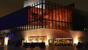 A modern building with a large glass facade, a spacious outdoor area with seating, and a visible entrance. - Charming Apaartment in Bremerhaven (Bremerhaven)