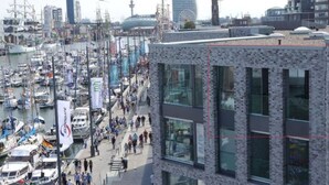 A marina with boats docked, a pedestrian walkway, and modern buildings with large windows. - Charming Apaartment in Bremerhaven (Bremerhaven)