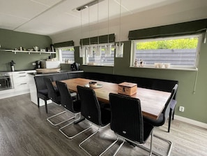 Una cocina moderna con comedor, que presenta una mesa de madera, sillas negras y un horno empotrado.