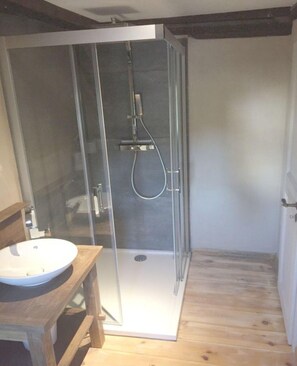 A modern bathroom with a glass-enclosed shower, a wooden vanity with a sink, and a wooden floor. - The old Cobbler House (Osterwieck)