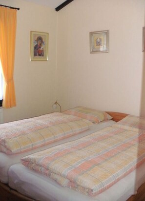 Un dormitorio con dos camas, una ventana con cortinas y dos cuadros en la pared.
