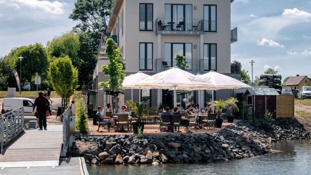 Un edificio moderno con terraza al aire libre y un muelle junto al agua.