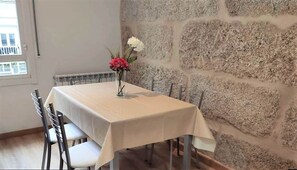 A dining table with a white tablecloth, chairs, and a vase with flowers. - Apartment in Ourense Near Thermal Baths (Ourense)