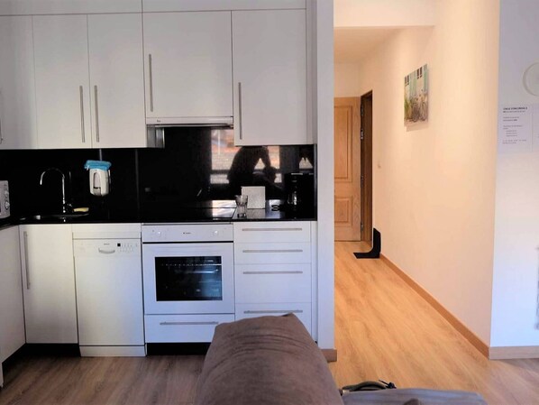 A compact kitchen with white cabinets, a black countertop, and a built-in oven. - Apartment in Ourense Near Thermal Baths (Ourense)