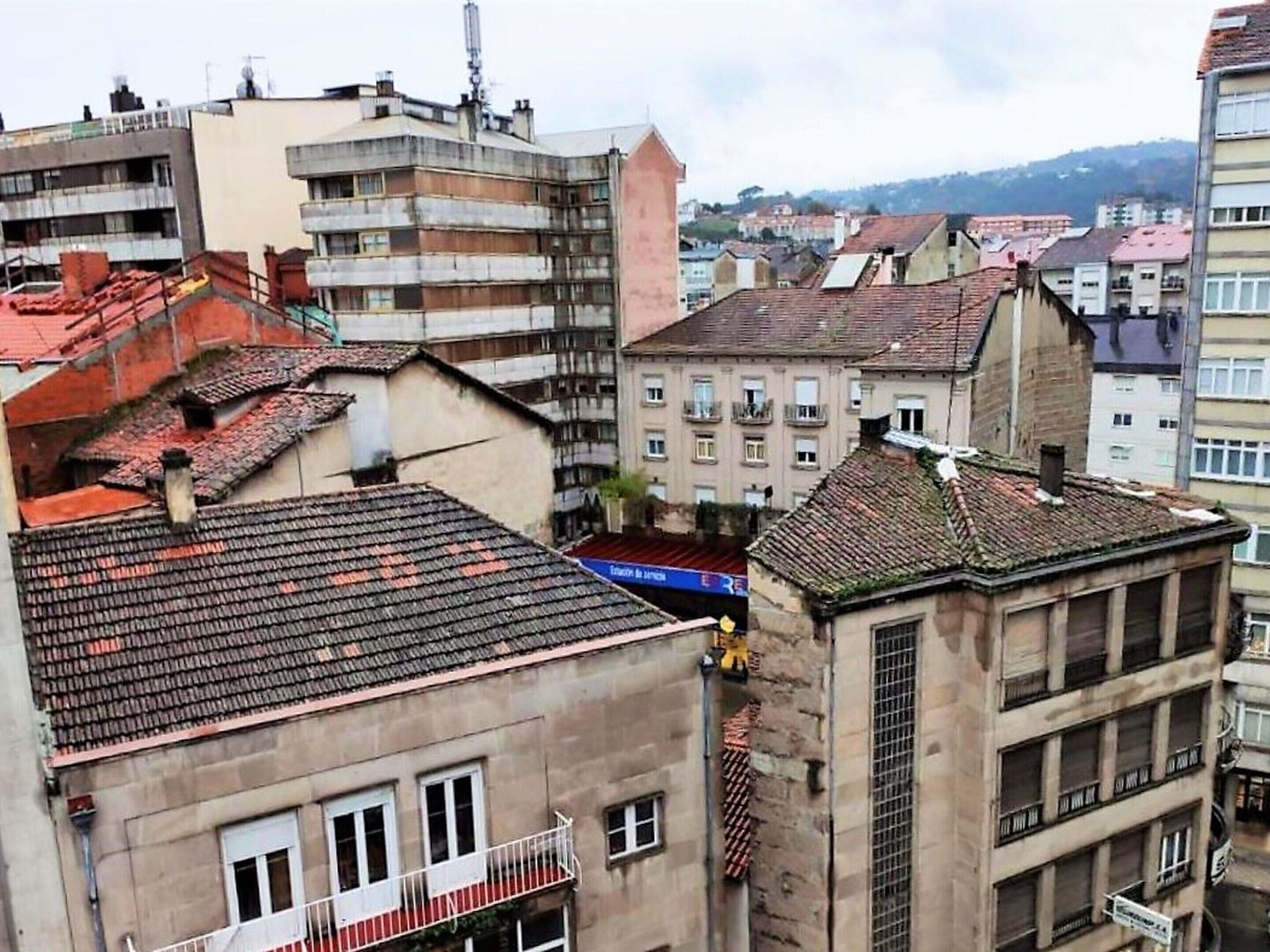 Un edifici de diversos pisos amb espais residencials i comercials, caracteritzat per diferents tipus de teulades i façanes.