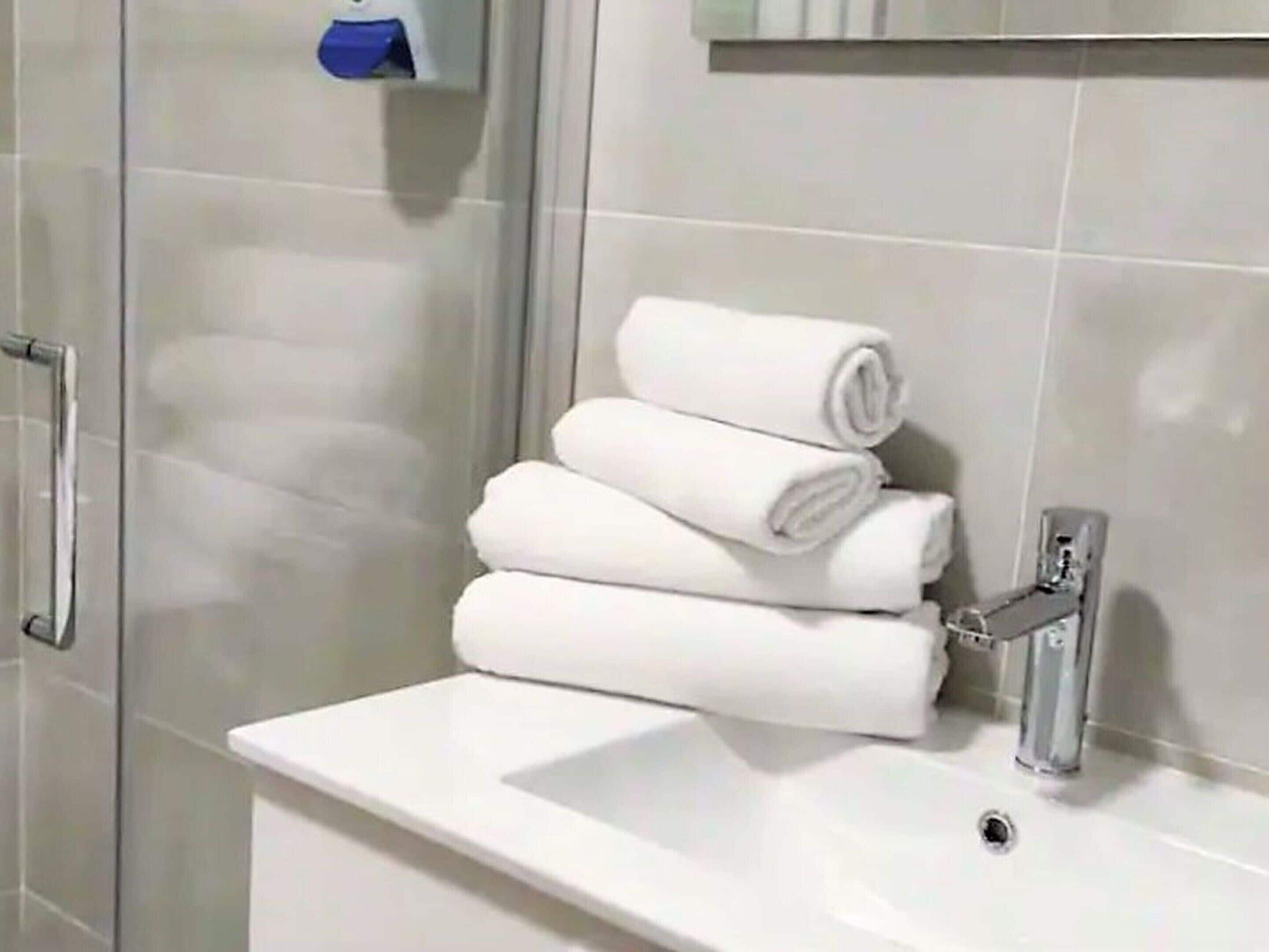 A bathroom with a white sink, a mirror, and a towel rack with folded towels.