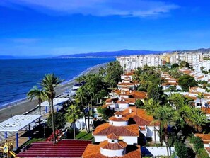 A coastal residential area with terraced houses, palm trees, and a beach. - Belvilla by OYO Casa Bonita I (Torrox)
