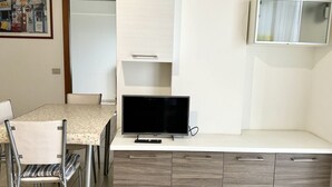 A dining area with a table, chairs, a television, and a cabinet. - P028 - Porto Recanati, comfortable two-room apartment a few minutes from the bea (Porto Recanati)