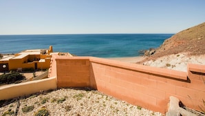 A coastal view with a clear sky, a sandy beach, and a rocky hillside. - Belvilla by OYO Chalet Corralete (Nijar)