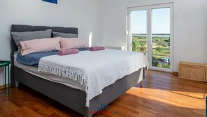 Une chambre avec un lit, une vue à travers une porte coulissante et une petite table d’appoint verte.