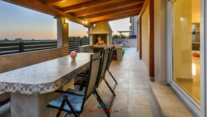 Une terrasse extérieure avec une table et des chaises en marbre, un barbecue et une vue sur le paysage.