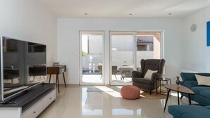 Un salon moderne avec un téléviseur à écran plat, un canapé, un fauteuil et une petite table.