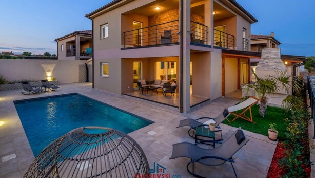 Une maison à deux étages dotée d’une piscine, d’un espace salon extérieur et d’une cheminée en pierre.