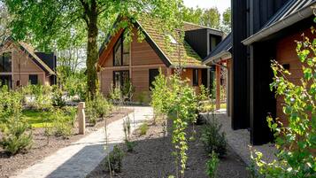 Een moderne woonwijk met verschillende houten huizen, een grindpad en kleine planten.